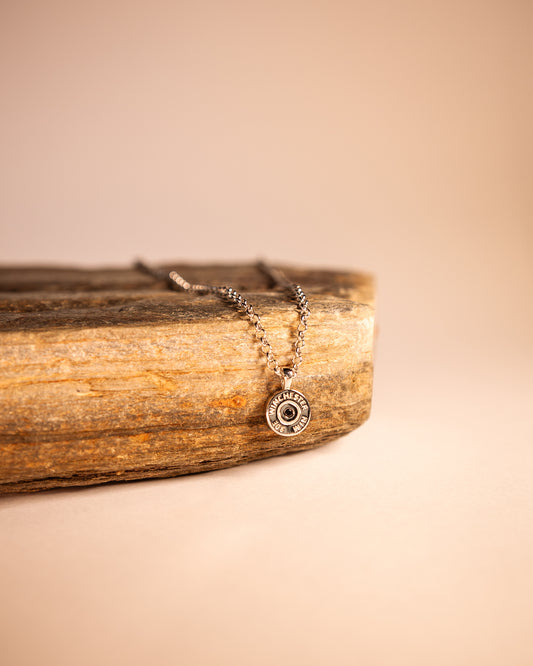 Winchester Bullet Necklace with a on a wooden surface