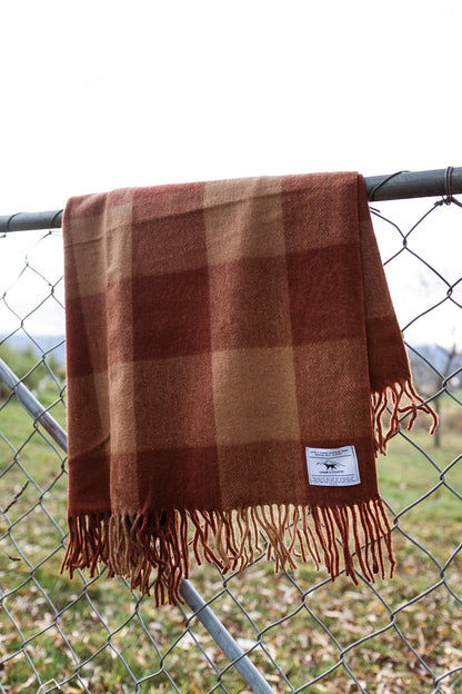 Recycled wool blanket hanging on a chain-link fence.